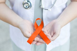 Female doctor in white uniform with orange ribbon awareness in hand as stop sign for ADHD,COPD,Cultural Diversity,Kidney Cancer – Renal Cell Carcinoma,Leukemia, Lupus,Malnutrition,Self Injury,Spinal