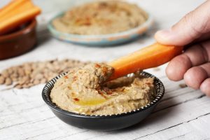 dipping carrot in a homemade lentil hummus