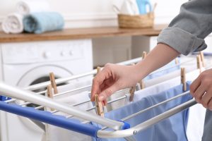Woman hanging clean laundry on drying rack in bathroom, closeup