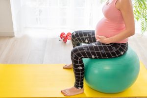 young pregnant woman sitting on a fitness ball does exercises to strengthen the pelvic floor in pregnancy during childbirth preparation classes