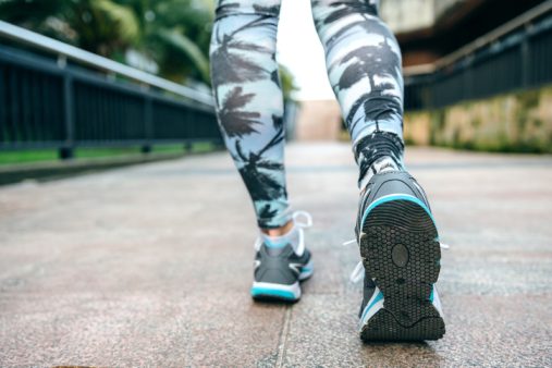 Woman legs ready to run wearing sneakers and tropical leggings