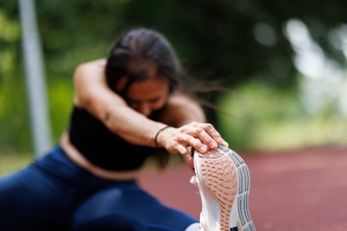 Qué son las agujetas y cómo aliviarlas Chica estírandose después de hacer deporte