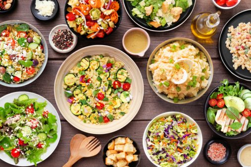 Assortment of delicious homemade salads. Top view table scene on a dark wood background.